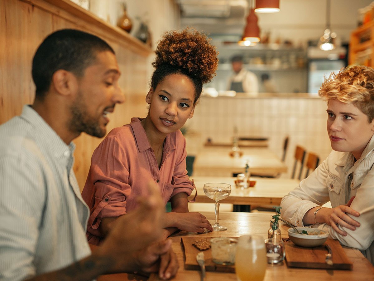 Three people talking around a restaurant table.